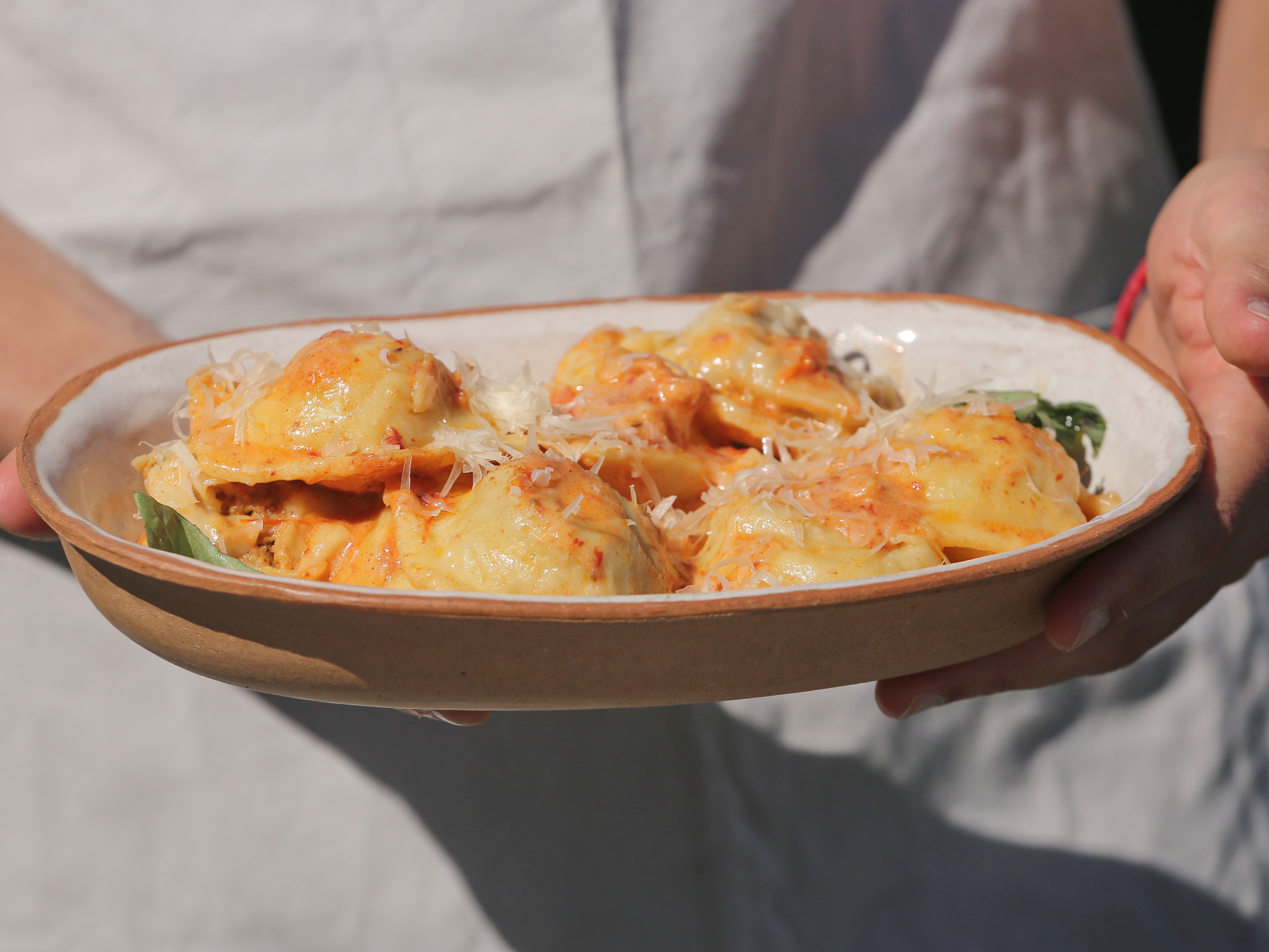 Capelacci relleno de bondiola a la cerveza negra con salsa de cebollas caramelizadas y sriracha