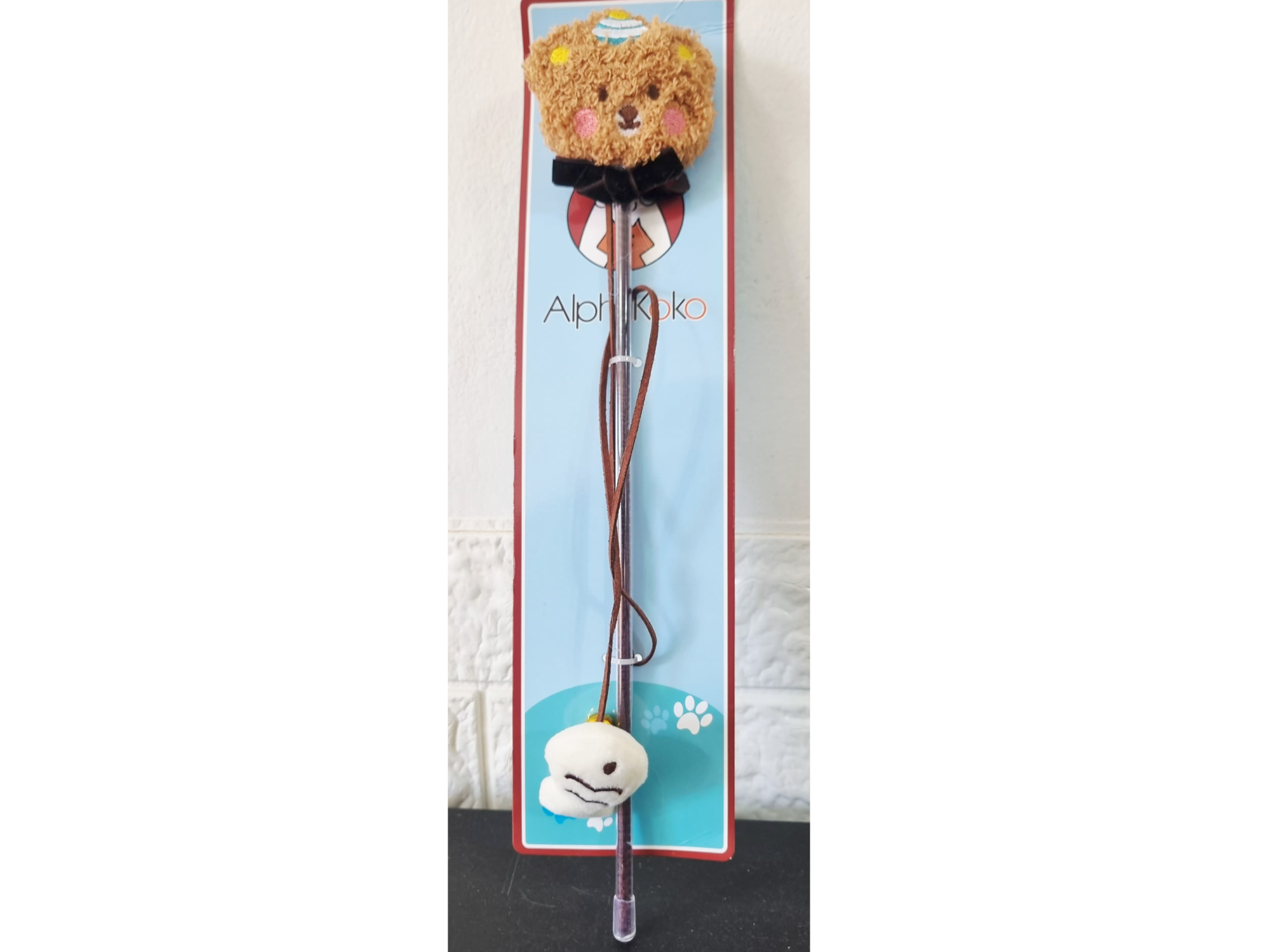 El diseño cuenta con un peluche suave en la parte superior y un colgante con cordón.