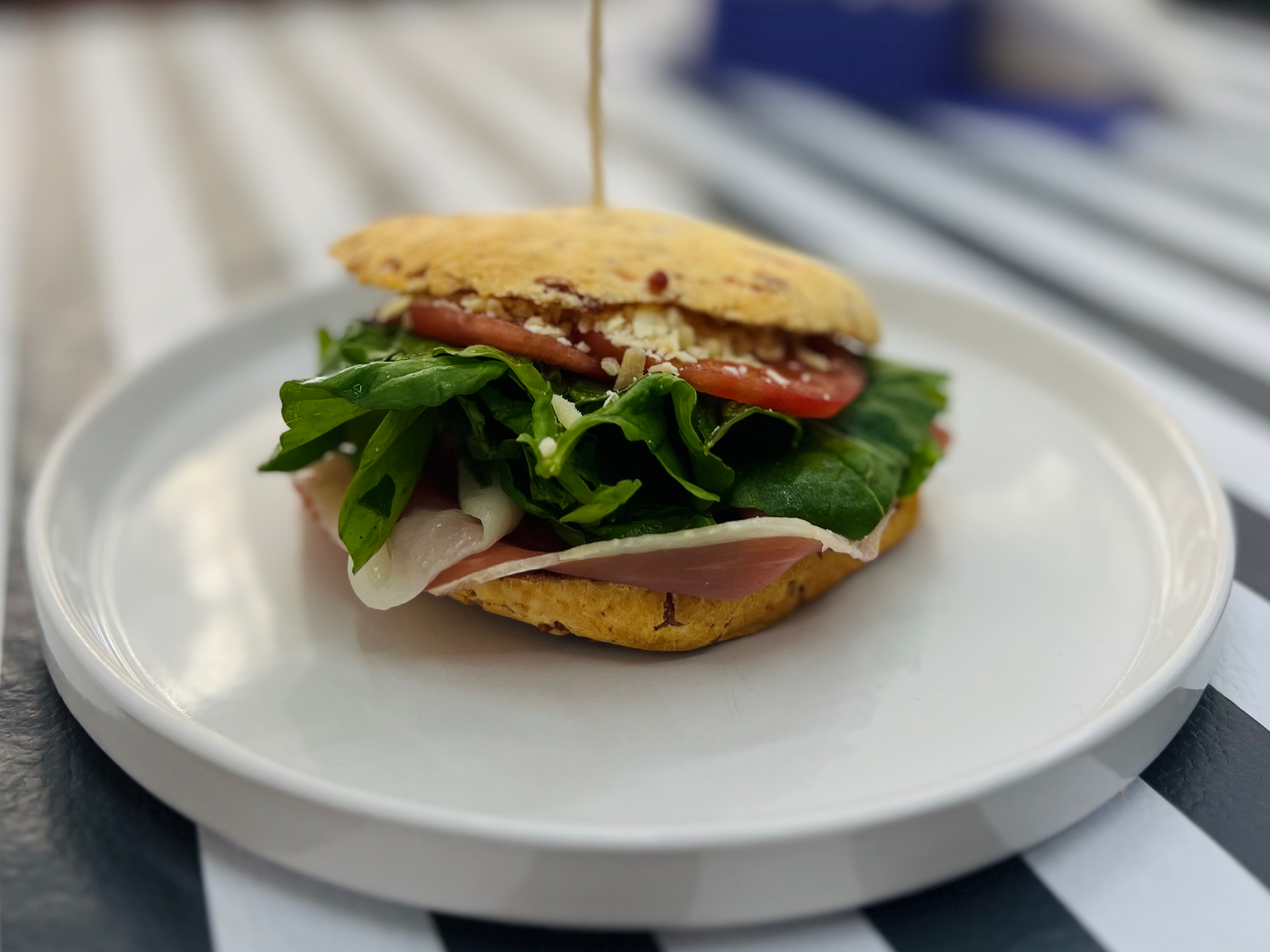 Sandwich de pan de chipa con jamon crudo, rúcula, tomate y parmesano