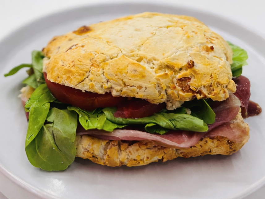 Sandwich de pan de chipa con jamon crudo, rúcula, tomate y parmesano