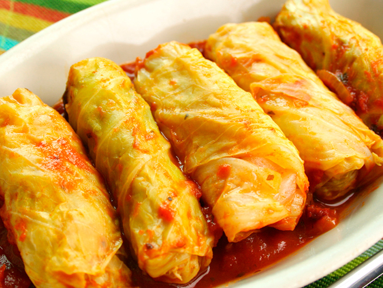 21. Niños envueltos con relleno de verduras asadas y queso sobre salsa roja.