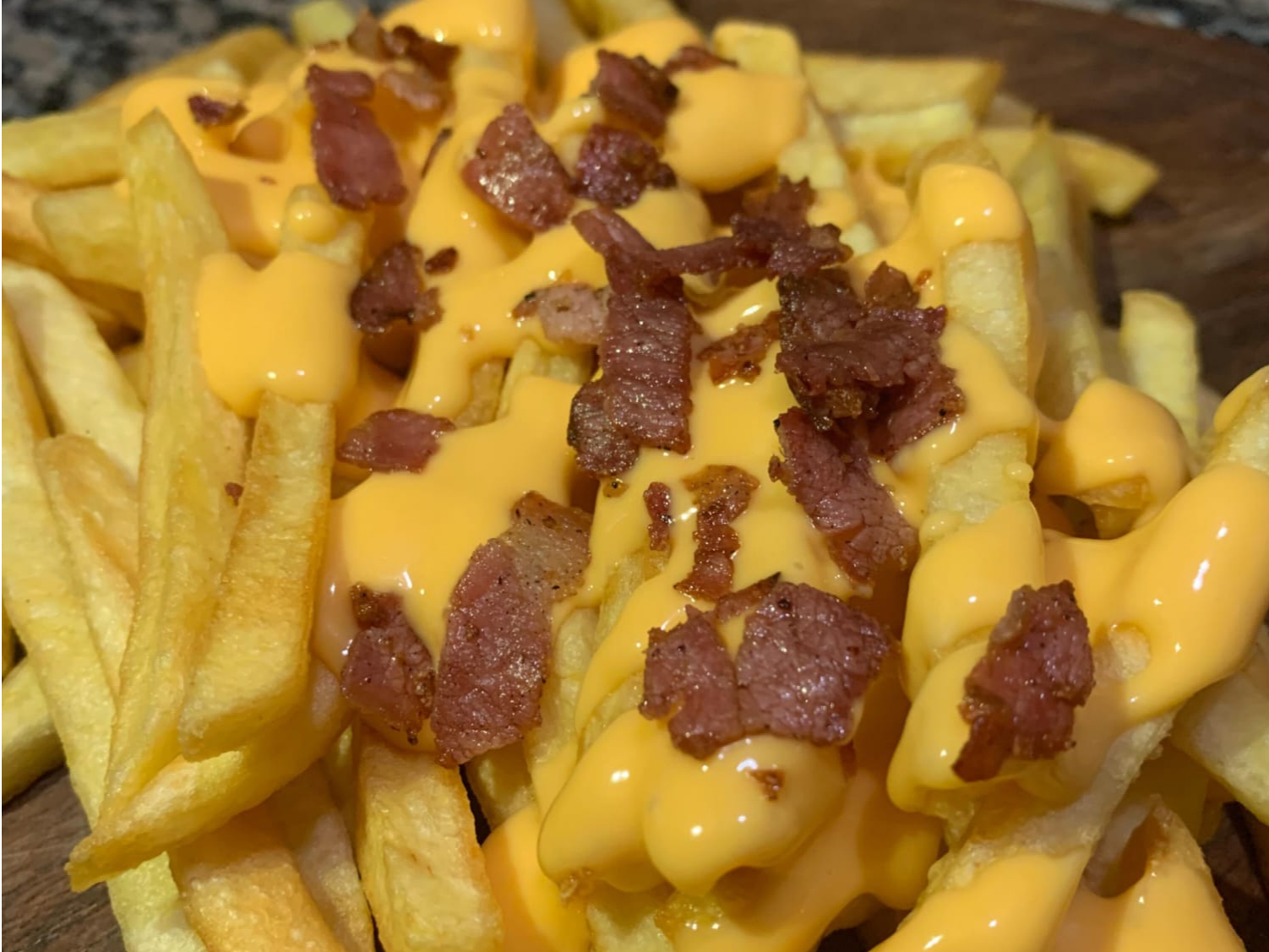 Porcion de papas fritas con cheddar y baccon
