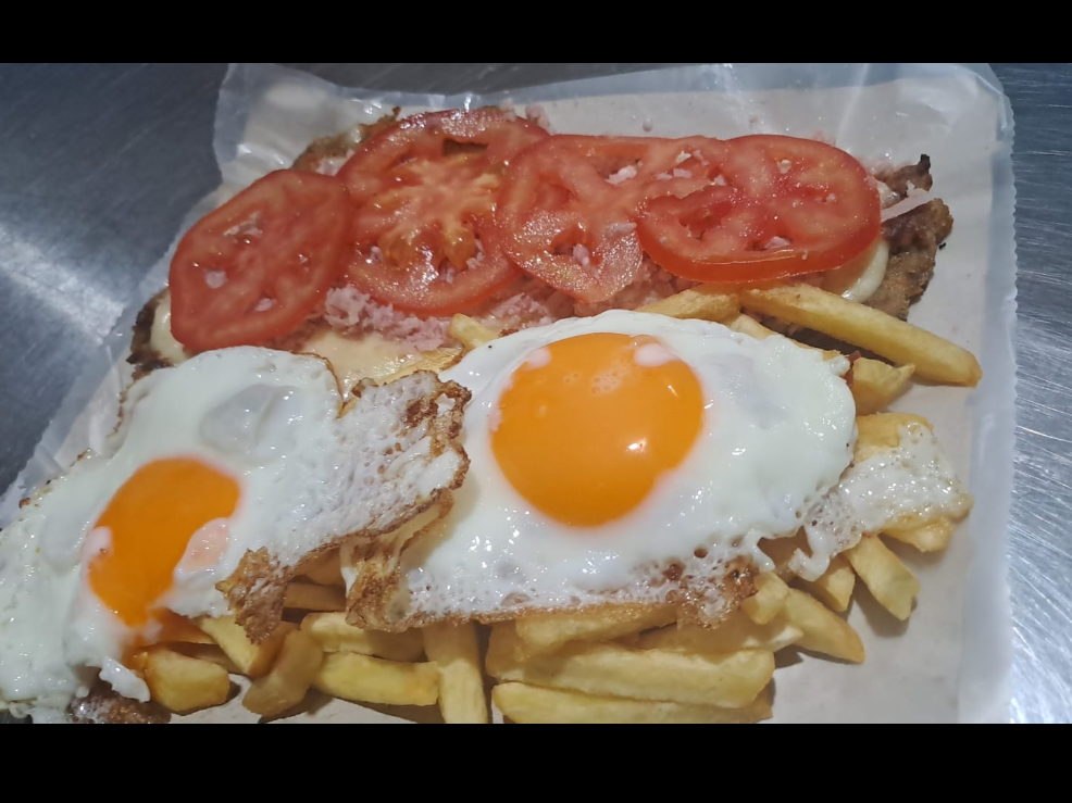 Milanesa napolitana con jamón y tomates más papas con 2 huevos fritos